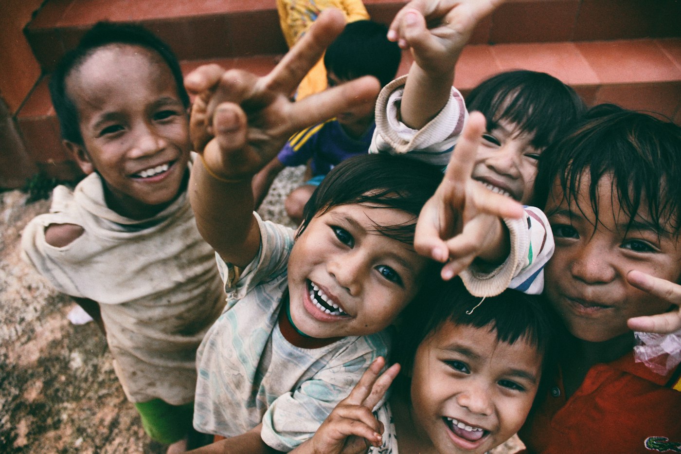 Children smiling despite worn clothes, looking up with hope