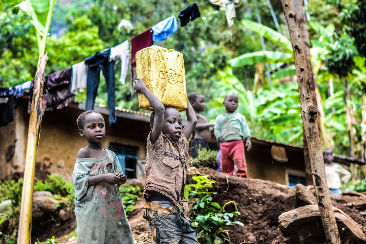 Boy carrying a yellow water jerrycan on his head