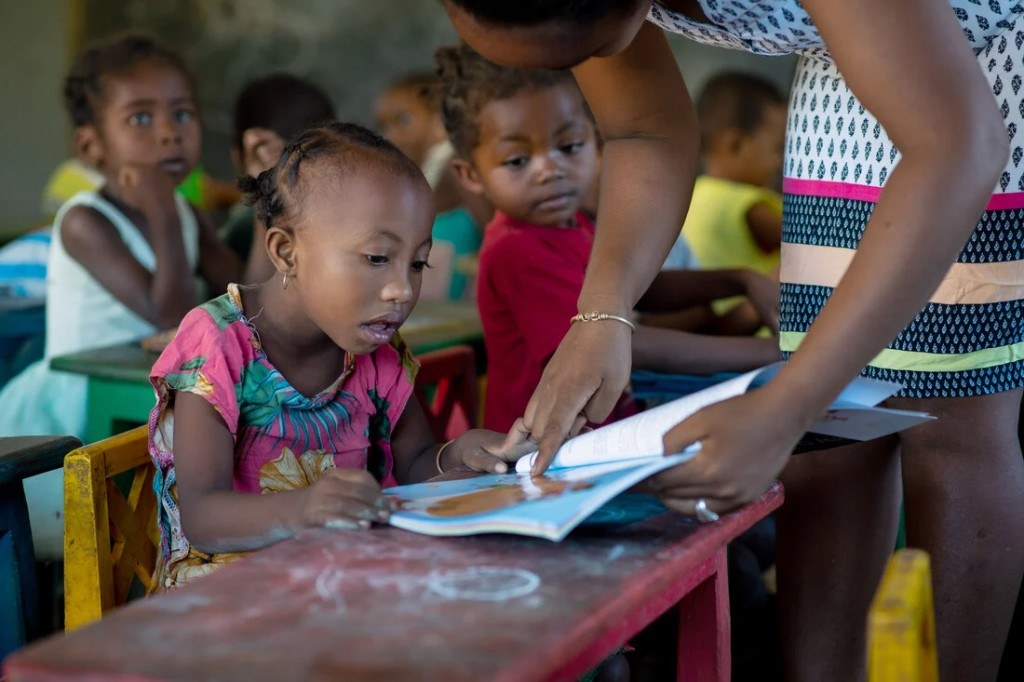 Child reading with a teacher in class